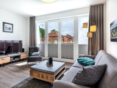 Wohn-/Essbereich mit Doppelschlafcouch, Couchtisch, TV und Zugang zum Balkon