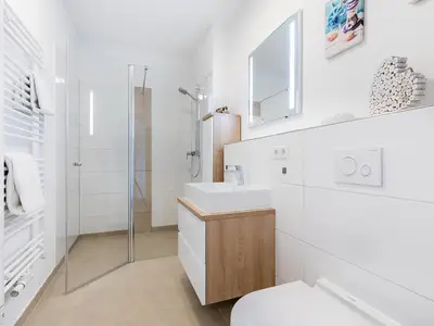 Badezimmer mit Dusche, Waschtisch, Spiegel und WC