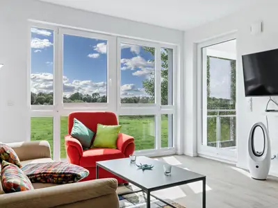 Wohn-Essbereich mit Couch, Flatscreen-TV und Zugang zum Balkon