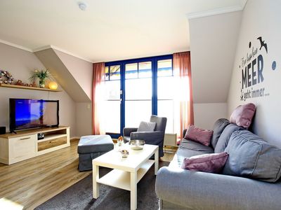 Wohnzimmer mit Sofa, Sessel und TV