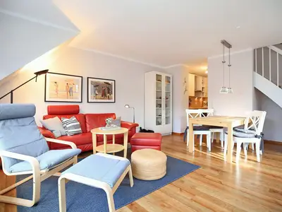 Wohnzimmer mit Sofa, Relaxsessel, Hocker und Essbereich