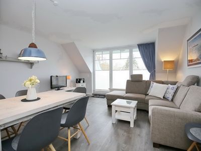 Wohnzimmer mit Sofaecke, TV, Esstisch und Blick zum Balkon