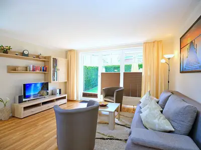 Wohnzimmer mit Schlafcouch, Sesseln und TV