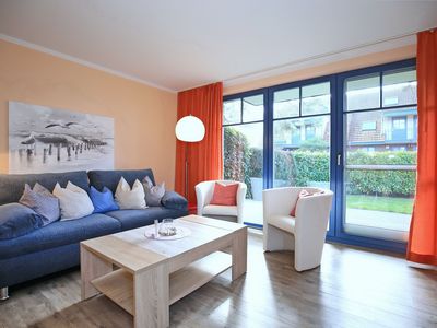 Wohnzimmer mit Schlafcouch und Sesseln mit Blick zur Terrasse