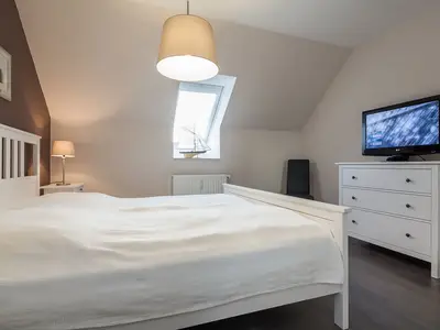 Schlafzimmer mit Doppelbett, Kommode und TV