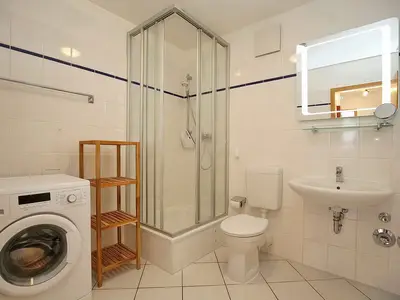 Badezimmer mit Dusche, WC, Waschbecken und Waschmaschine