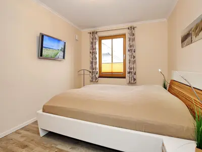 Schlafzimmer mit Doppelbett und TV
