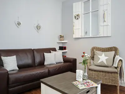 Wohnzimmer mit Schlafcouch und Korbsessel