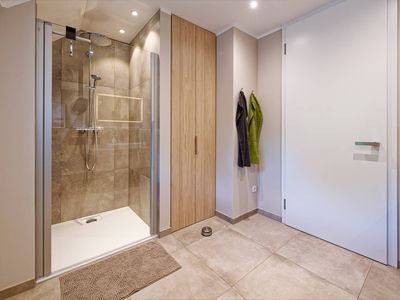 Badezimmer mit Regendusche und Waschmaschine im Wandschrank