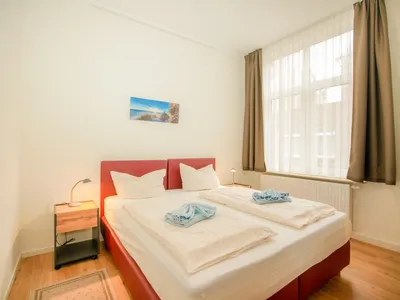 Blick von der Tür auf Boxspringbett und Fenster