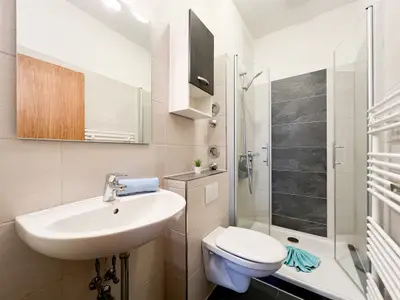 Badezimmer mit Waschbecken, WC und Duschkabine