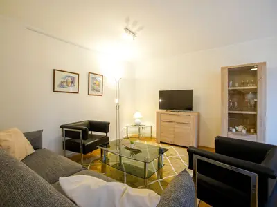 Wohnzimmerecke mit Sofa, Sesseln und Kommode mit TV