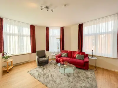 Weitwinkelaufnahme des Wohnzimmers mit Sofa und Sessel
