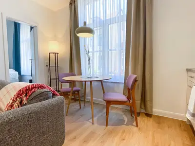 Blick auf Sofa und Esstisch mit zwei Stühlen