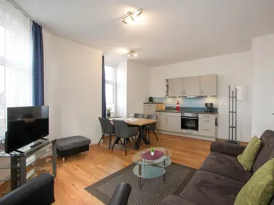 Blick vom Sofa Richtung Esstisch mit vier Stühlen und Küchenzeile