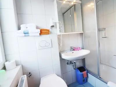 Badezimmer mit Föhn, Handtüchern und Dusche mit hohem Einstieg