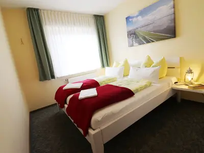 Schlafzimmer mit Doppelbett, bezogenes Bett, Nachttisch mit Tischleuchte