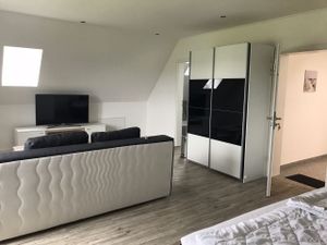 offener Wohnraum mit Boxspringbett und Schlafsofa