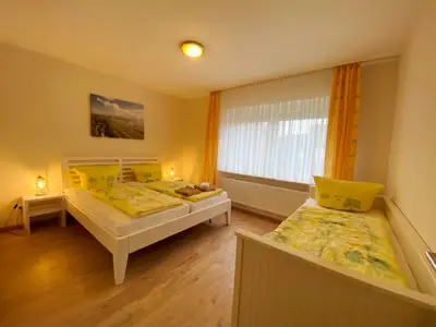 Schlafzimmer mit Doppelbett, extra Bett, Nachttisch mit Tischleuchte