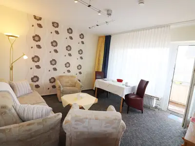 Wohnzimmer mit Esstisch, Sofa und Balkon