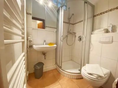 Badezimmer mit Dusche, Toilette, Wachbecken und Handtüchern