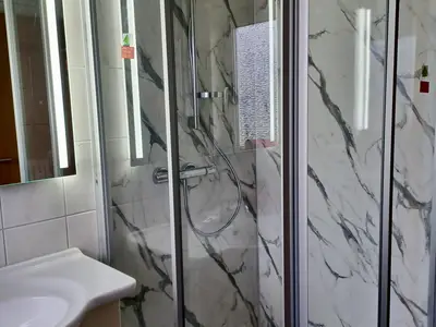 Moderne Dusche mit extraflacher Duschtasse und sanftem Wasserfluss – ideal zum Erholen nach einem langen Spaziergang am Meer.