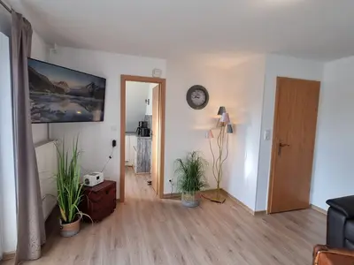 Wohnzimmer mit Fernseher und Blick in die Küche