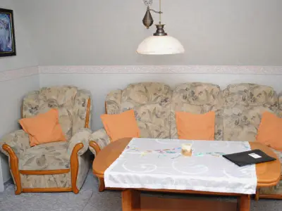 Wohnzimmer mit Küchenzeile FlachbildTV und Couchgarnitur zum gemütlichen Sitzen