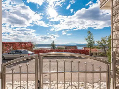 Blick durch das Eingangstor auf das Meer(parkplätze) und die Insel Krk