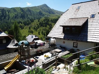 Ausblick vom Spielplatz auf die große Sonnenterrasse mit Tischtennis, Sandkiste, Rutsche, Griller,...