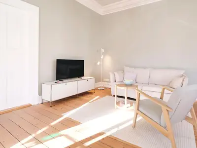 Wohnzimmer mit Couch, Esstisch und TV