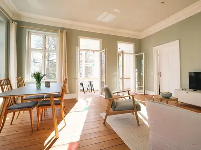 Wohnzimmer mit Couch, Esstisch und TV