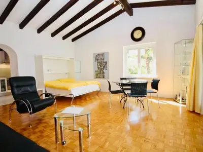 Die Sonne scheint durch das Seitenfenster. Zeitloses Interieur mit rundem Glastisch.