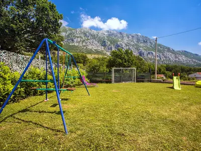 Kinderspielplatz mit Schaukel und Rutsche und Fußballplatz.