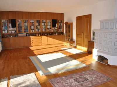 geräumiges Wohnzimmer mit Bücherwand und Kachelofen