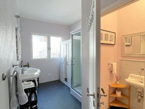 Grosses Badezimmer mit zwei Fenstern, Schrank, Kommode und Rollconteiner. Das WC mit Lavabo ist in einem separaten Raum.