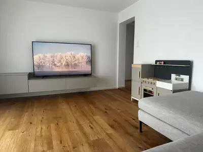 Wohnzimmer mit direktem Zugang zum Balkon, atemberaubendem Bergpanorama und Swisscom-TV-Anschluss für beste Unterhaltung