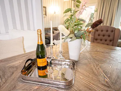 Nautic Lounge – Beach View: Champagner & Gläser auf stilvollem Esstisch mit Blumendeko.