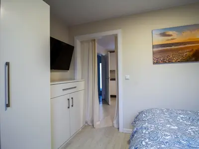 Schlafzimmer der Nautic Lounge – Beach House 2 mit Smart-TV, Kleiderschrank und modernem Ambiente.