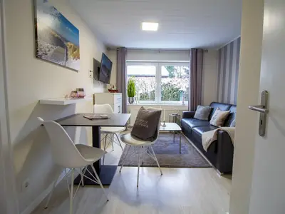 Gemütlicher Wohn- und Essbereich der Nautic Lounge – Beach House 1 mit Schlafsofa, Smart-TV und modernem Interieur.