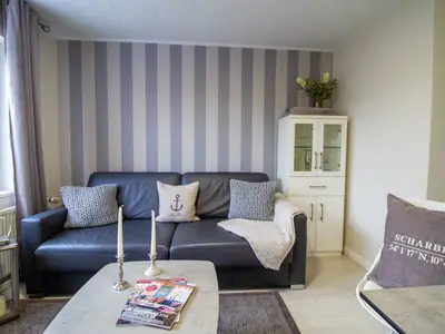 Stilvoller Wohnbereich der Nautic Lounge – Beach House 1 mit gemütlichem Sofa, maritimer Deko und eleganter Vitrine.