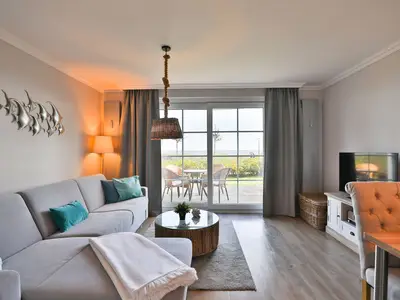 Strandmuschel Haffkrug: Modernes Wohnzimmer mit Zugang zur Terrasse und Ostseeblick.
