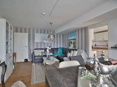 Nautic Lounge – Sea View: Helles Wohnzimmer mit gemütlicher Sofaecke und direktem Zugang zur Küche.