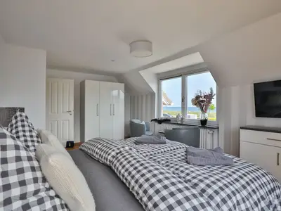 Nautic Lounge – Sea View: Helles Schlafzimmer mit Boxspringbett, Meerblick und TV.