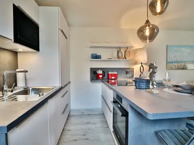 Nautic Lounge – Beach Garden: Moderne, voll ausgestattete Küche mit stilvollem Essbereich in Haffkrug.