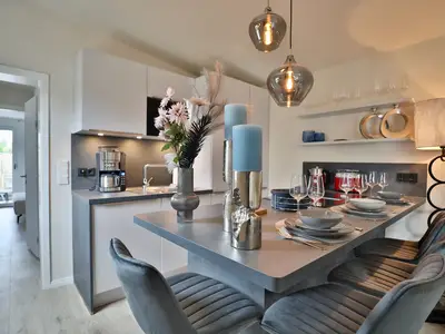 Nautic Lounge – Beach Garden: Moderne Küche mit Esstresen und Blick ins Schlafzimmer in Haffkrug.