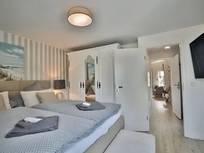 Nautic Lounge – Beach Garden: Schlafzimmer mit Doppelbett, Landhausstil-Schrank und TV in Haffkrug.
