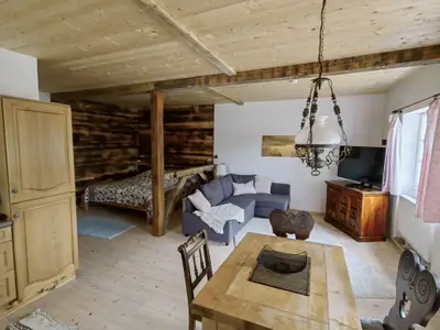 Blick ins Appartement bei Eintritt - Essplatz mit Wohnbereich dahinter und durch Balken getrennte Schlafecke
