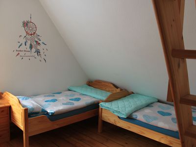 Schlafzimmer mit zwei Einzelbetten und Treppe zum Spitzboden