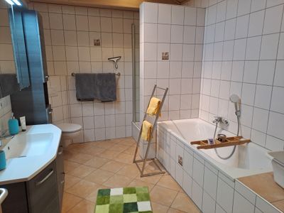 Das große Badezimmer hat eine Dusche, eine Badewanne, eine Waschmaschine und ein Dachfenster zum Lüften